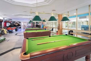A pool hall with multiple pool tables, green felt tables, and overhead green lamps. - Beautiful 1-bedroom apartment in Benalbeach (Benalmádena Costa)