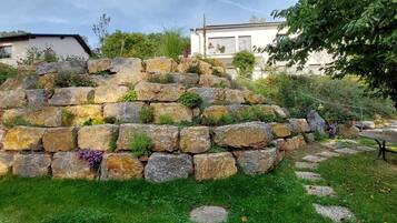 Ein Garten mit einer Steinmauer, einem Baum und einem Tisch.