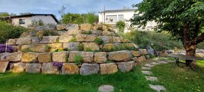 Ein Garten mit einer Steinmauer, einem Baum und einem Tisch.