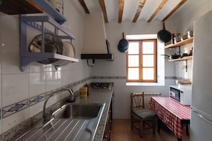 A kitchen with a sink, stove, and a window.