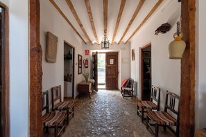 A hallway with wooden beams, stone flooring, and chairs with striped cushions. - Casa del Labrador - Finca & Spa Vereda Real (Albacete)