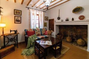 A traditional room with a fireplace, a sewing machine, a sofa, and a dining table.