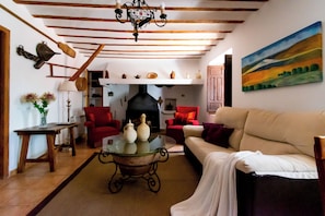A living room with a sofa, chairs, a glass coffee table, and a fireplace.