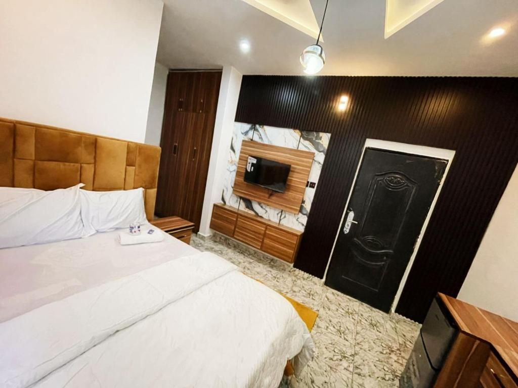 Une chambre à coucher avec un lit, un téléviseur fixé au mur, une armoire et une porte.