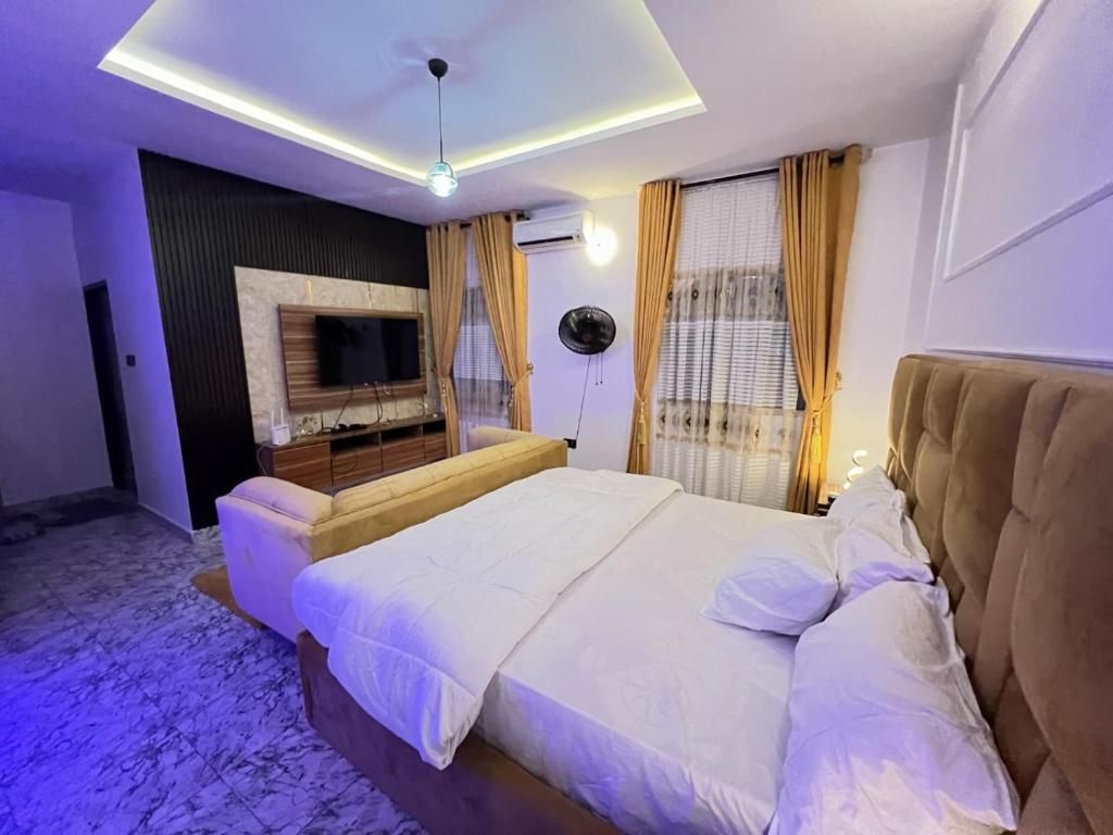Une chambre à coucher moderne avec un lit, un téléviseur fixé au mur et un luminaire au plafond.
