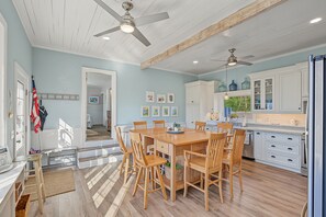 Une cuisine spacieuse dotée d’un plancher en bois, de meubles blancs et d’un coin repas avec des chaises en bois.