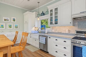 Une cuisine avec des meubles blancs, une cuisinière en acier inoxydable et un dosseret de carrelage bleu.