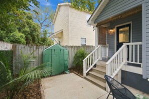 A residential property with a covered patio, a wooden fence, and a green garden shed. - NEW! Row & Behold - We love Dogs! (Wilmington)