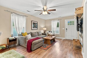 A living room with a ceiling fan, a sofa, a coffee table, and a door with a window. - NEW! Row & Behold - We love Dogs! (Wilmington)