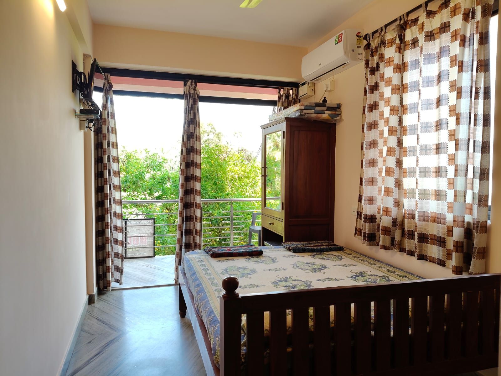 Un dormitorio con cama, armario y balcón con cortinas.