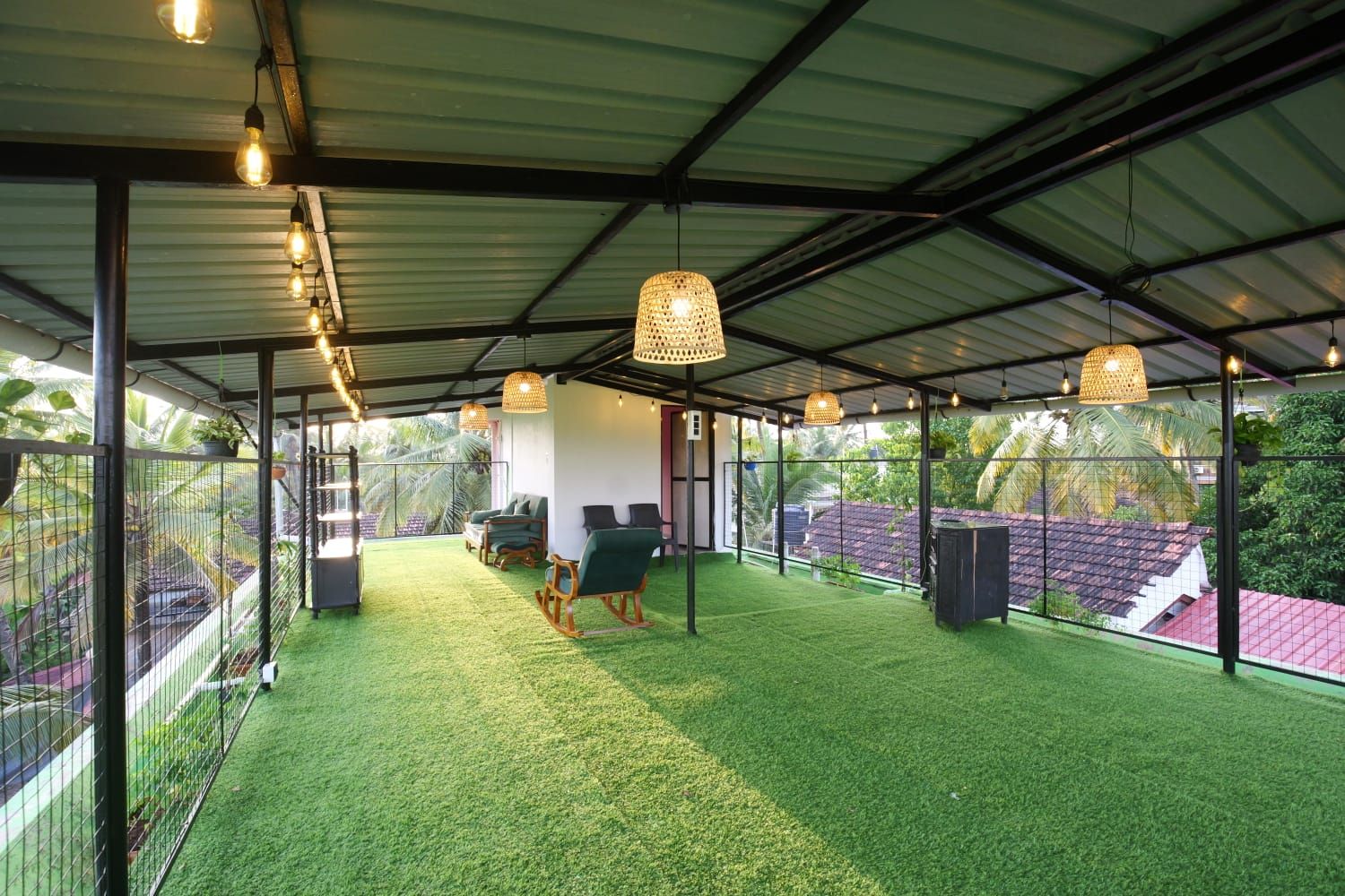 A covered outdoor area with artificial grass, seating, and hanging lights.