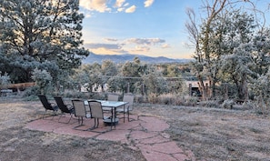 An outdoor patio with a table and chairs, surrounded by trees and a view of mountains. - Amazing central location across from CU Boulder (Boulder)
