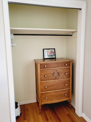A wooden dresser with drawers and knobs, placed in a corner with a white wall and wooden flooring. - Amazing central location across from CU Boulder (Boulder)