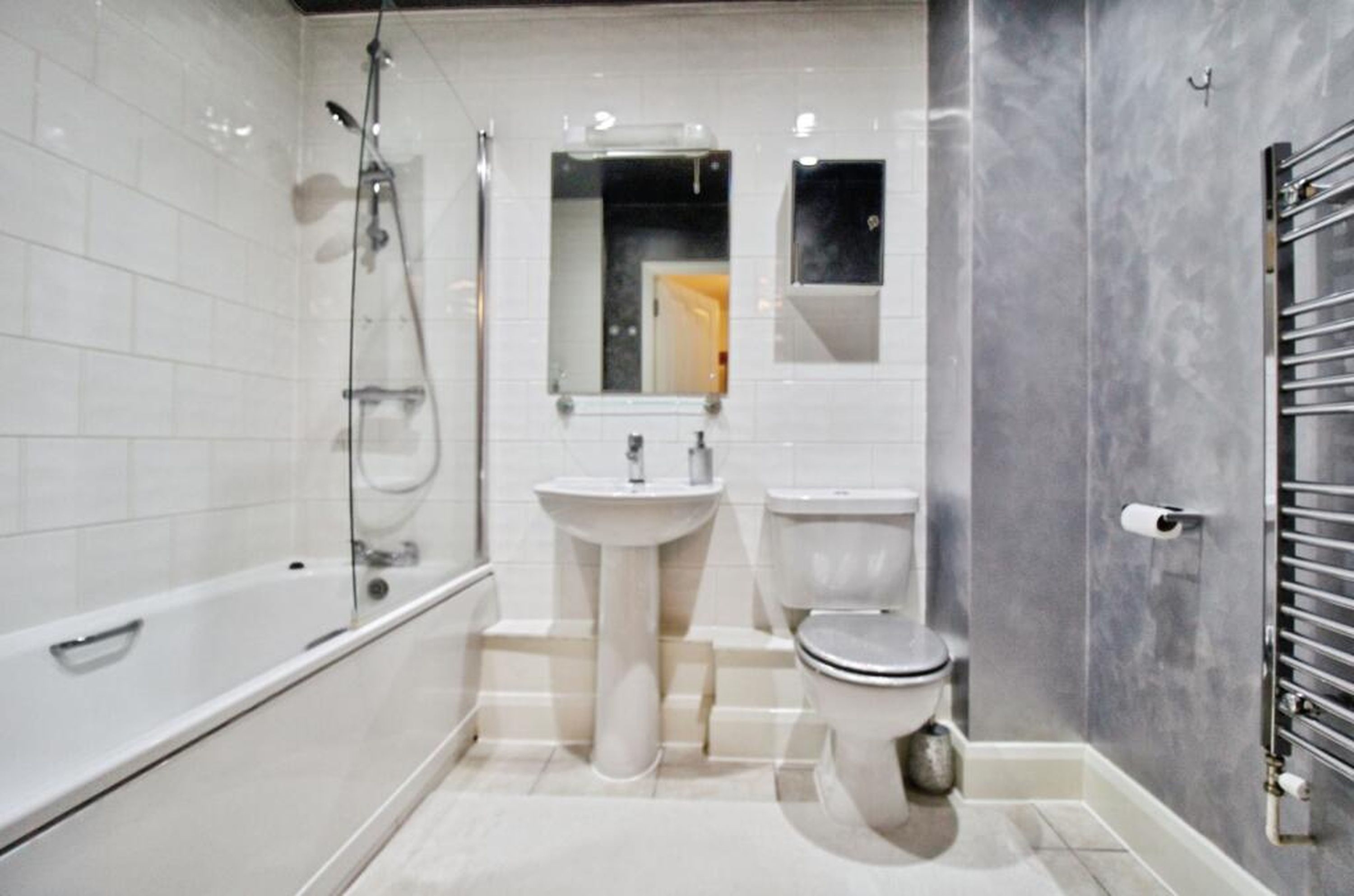 A modern bathroom with a glass-enclosed shower, a pedestal sink, and a toilet.