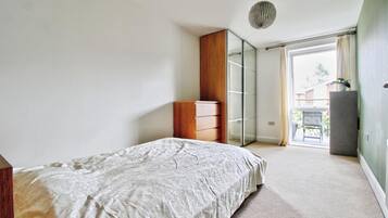 A bedroom with a bed, a wardrobe, a mirror, and a door leading to a balcony.