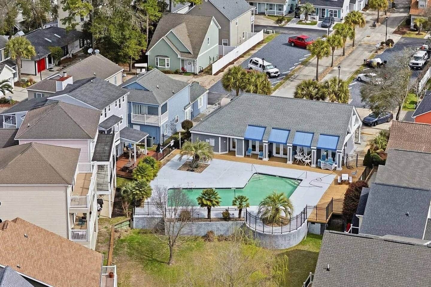 A residential area with multiple houses, a swimming pool, and a fenced patio area.