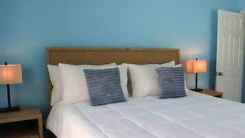 A bed with a wooden headboard, two bedside lamps, and a white door.