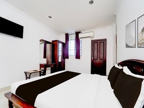 A hotel room with a bed, a desk, a mirror, a wardrobe, and a door. - Collection O Infopark Kochi (Kanayannur)