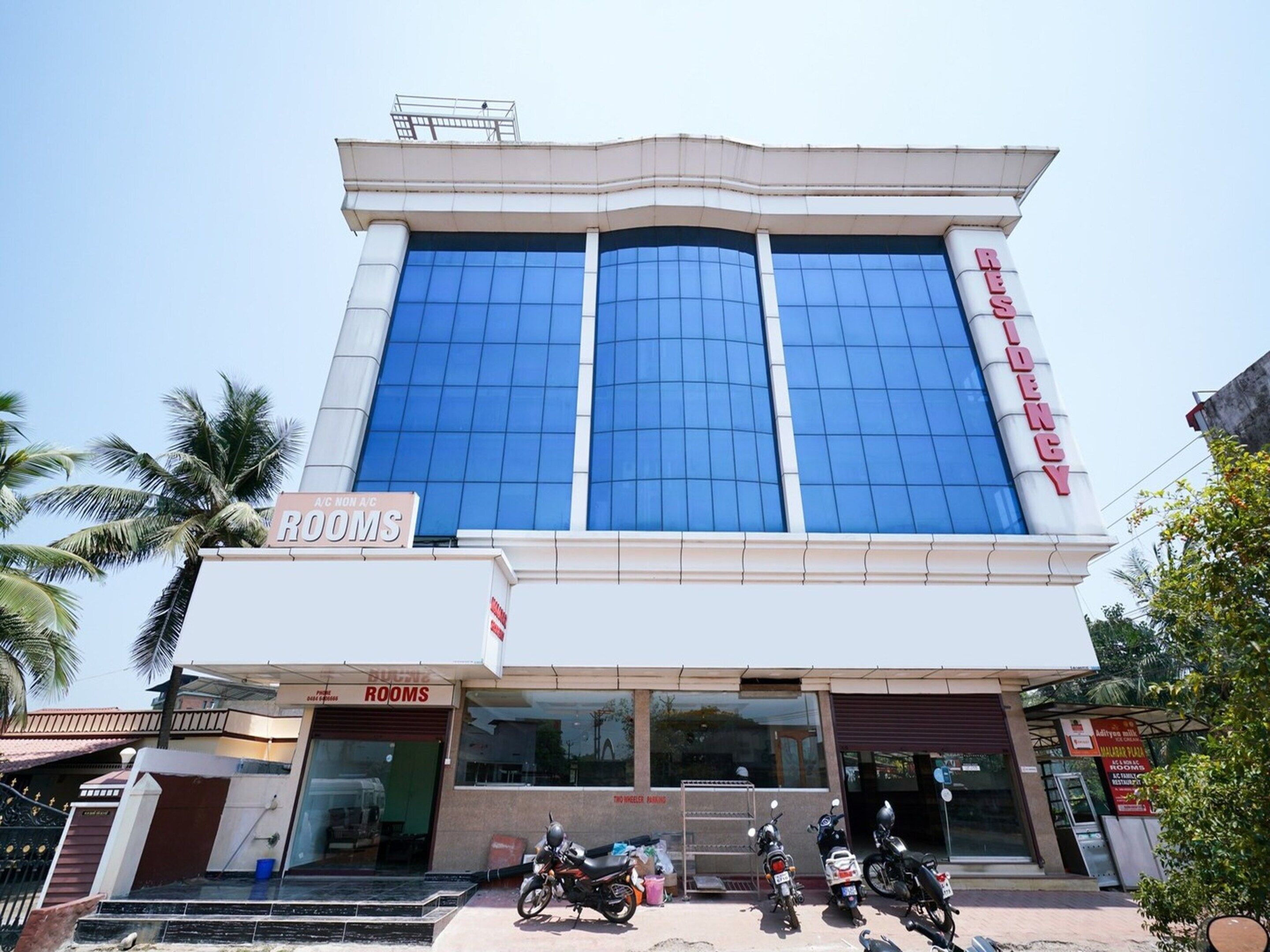 A hotel with a prominent 'HOTEL' sign on the facade, a 'ROOMS' sign below, and several motorcycles parked in front.