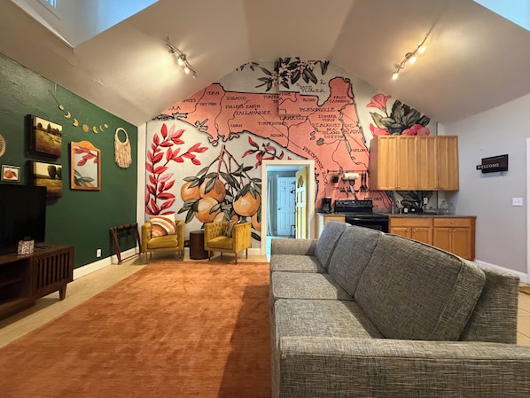 Un salon avec un mur vert, une fresque représentant une carte, un canapé et une table basse.