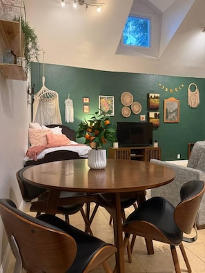 Un espace repas comprenant une table ronde et des chaises, un téléviseur et des éléments décoratifs sur les murs.