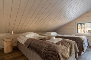 A cozy attic bedroom with two beds, wooden beams, a window, and a lamp. - Alpine South Slope A7 by Aavalevi (Levi)