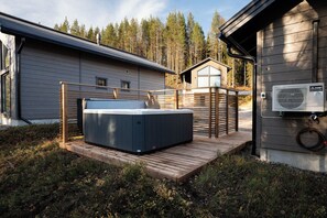 A hot tub on a wooden deck, a sauna, and a building with a sloped roof. - Alpine South Slope A7 by Aavalevi (Levi)