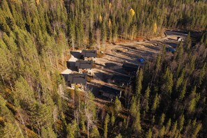 An aerial view of a forested area with a cluster of buildings, likely a cabin or lodge, surrounded by dense trees. - Alpine South Slope A7 by Aavalevi (Levi)