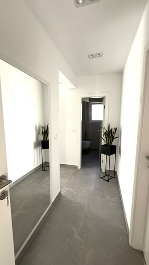 A hallway with a modern design, featuring a large mirror, a potted plant, and a door leading to a bathroom. - Apartment 'Terrace  Makarska' with Sea View, Wi-Fi and Air Conditioning (Makarska)