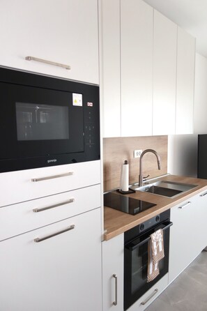 Eine moderne Küche mit Einbauofen, Mikrowelle und Spülbecken aus Edelstahl.