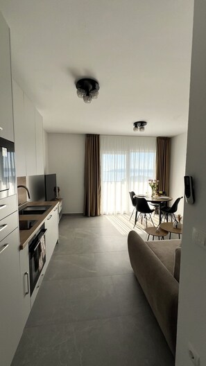 A modern kitchen with a built-in oven, a dining area with a table and chairs, and a sofa. - Apartment 'Terrace  Makarska' with Sea View, Wi-Fi and Air Conditioning (Makarska)