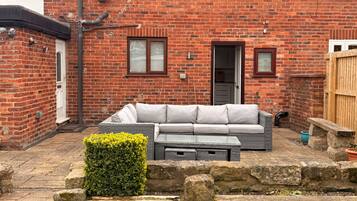 A brick house with a grey sofa set in the backyard.