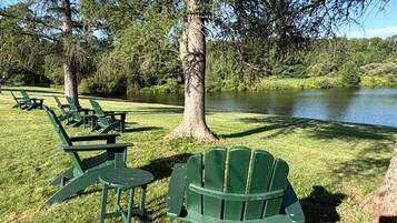 Un parco con sedie e tavoli disposti sull'erba, vicino a un corso d'acqua.