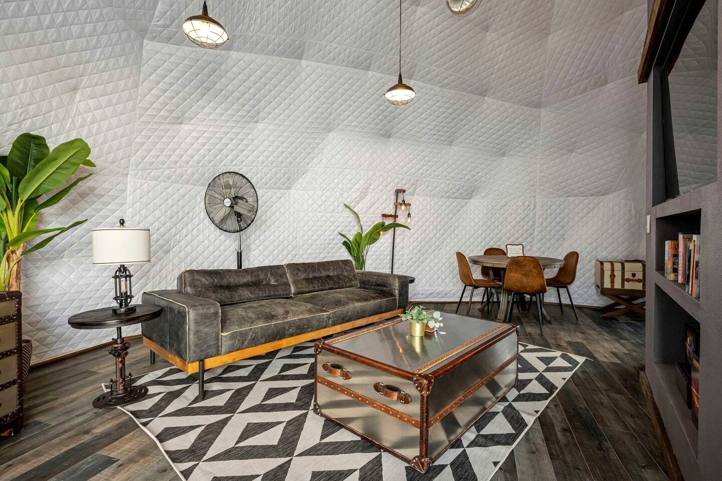 A cozy living room with a sofa, coffee table, and a dining area with chairs and a table.