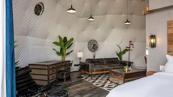 A room with a quilted ceiling, a sofa, a coffee table, a desk, and a bed.