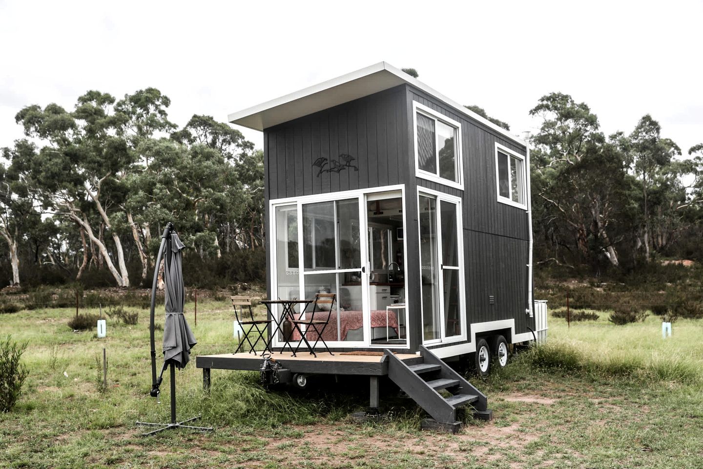 A modern, two-story cabin with a deck and a covered outdoor seating area.