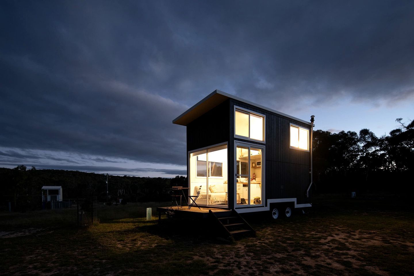 A modern, two-story house with a flat roof, large windows, and a small porch area.
