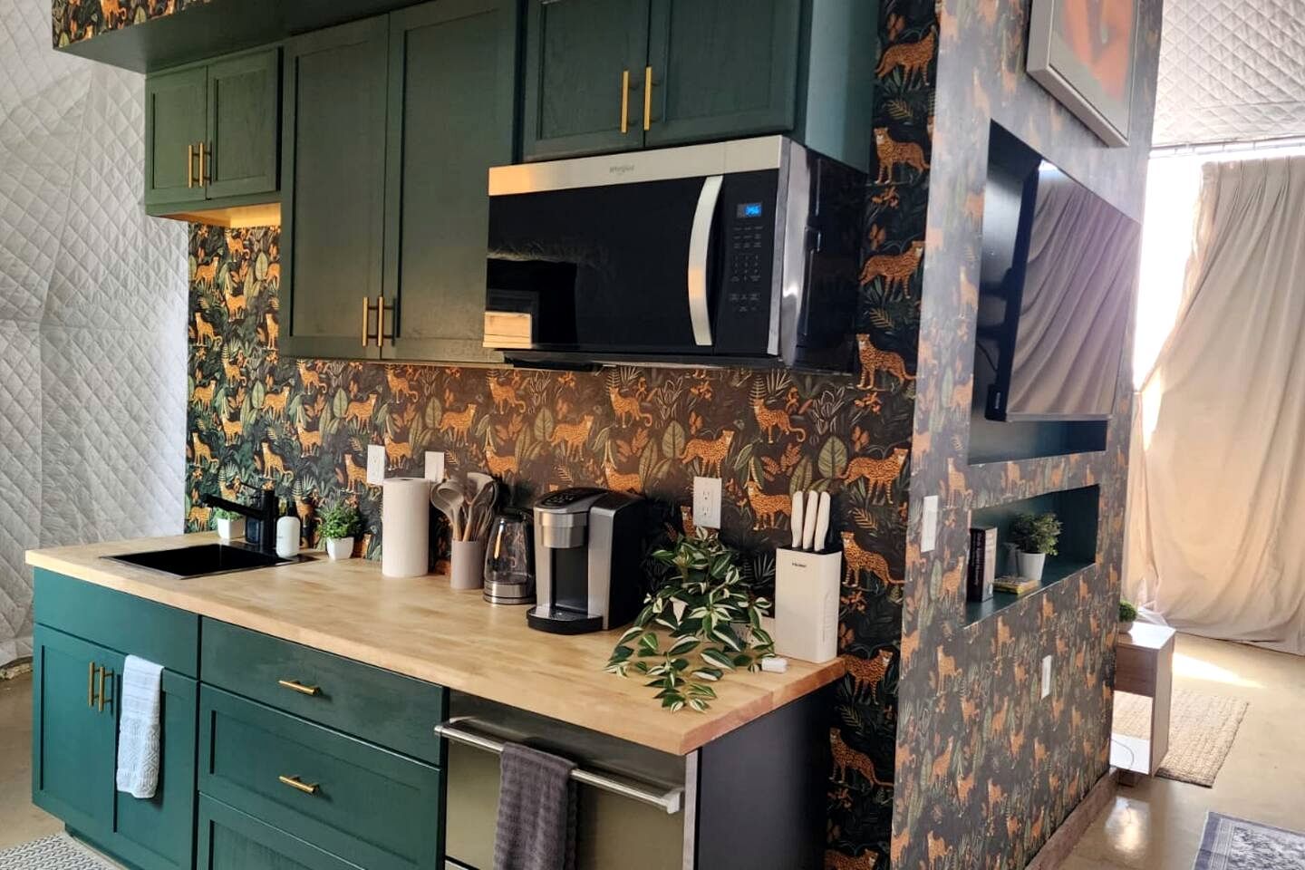 A kitchen with green cabinets, a microwave, and a coffee maker.