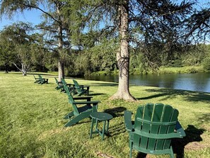 A park with green Adirondack chairs and a lake.