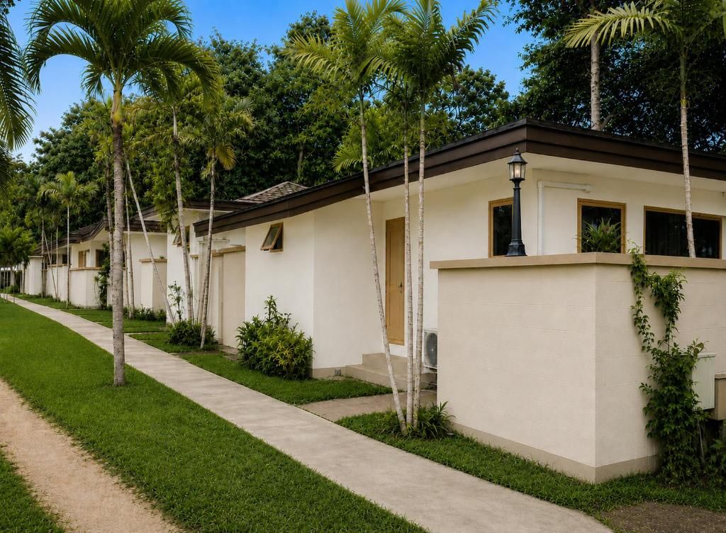 A row of single-story buildings with a uniform architectural style, surrounded by well-maintained greenery and a clear sky.