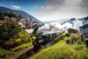 A steam train passing through a rural area with houses and a church. - 071 Whkb 18a in St Georgen am Kreischberg (Sankt Georgen am Kreischberg)