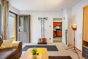 A modern living room with a sofa, a coffee table with a plant, a floor lamp, and a view into the kitchen. - Holiday Apartment 'Eselei' with Shared Garden and Wi-Fi (Belm)