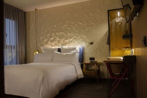 A hotel room with a bed, a desk, a chair, a mirror, and a window with curtains. - LETOH Ribeira (Porto)