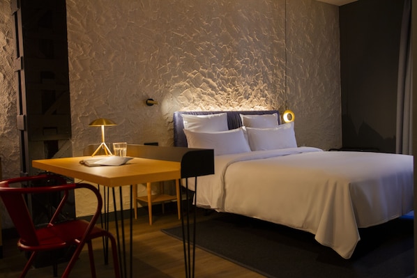 Una habitación de hotel con una cama, un escritorio, una silla y una lámpara.