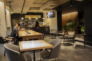 A modern cafe with a wooden table and chairs, a coffee bar, and a TV mounted on the wall. - LETOH Ribeira (Porto)