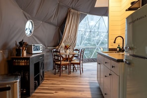 Una cocina compacta con comedor, ventana con vista a árboles y un horno pequeño.