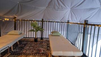 Una habitación con carpa, dos camas, un tapete estampado y una planta en maceta.