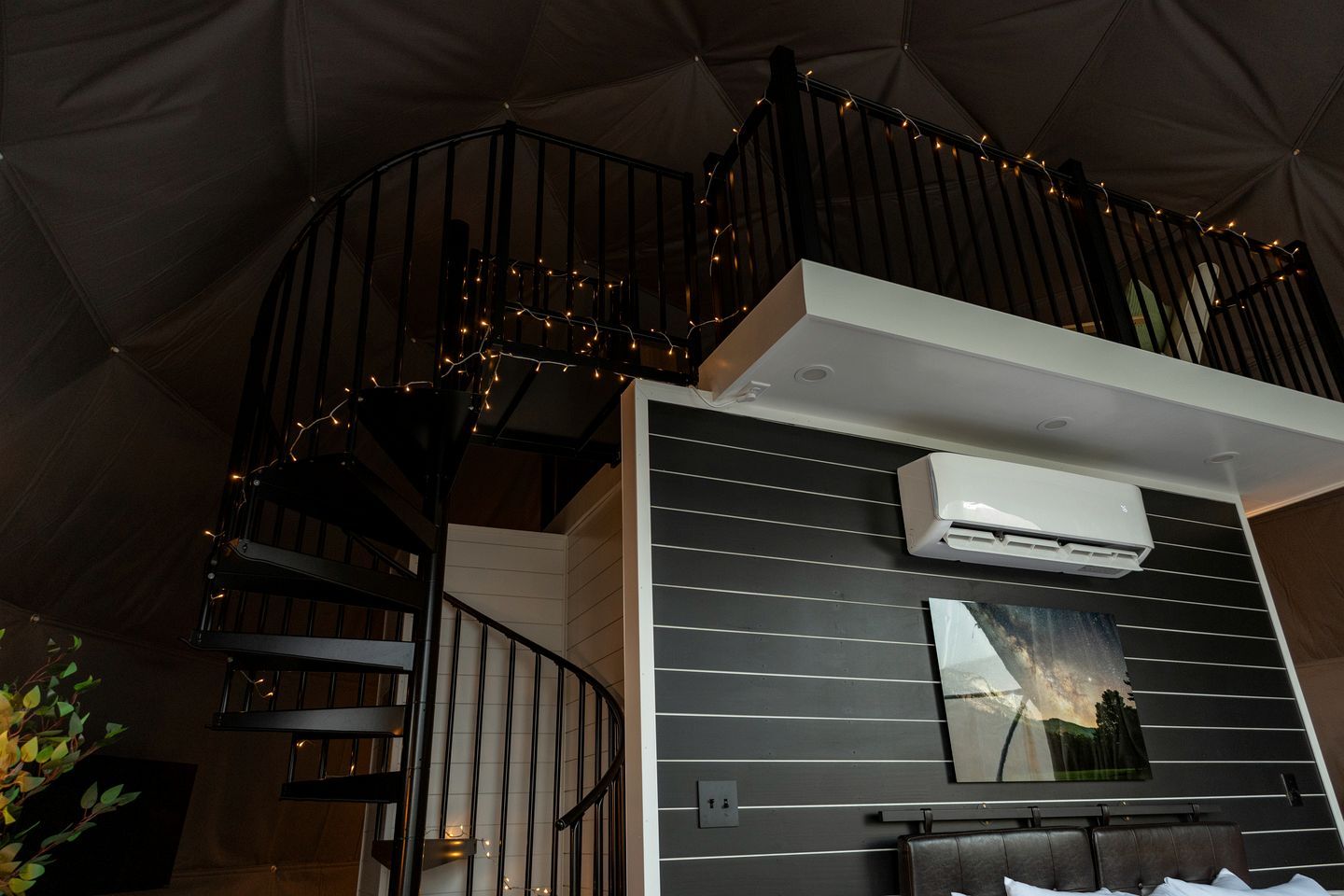 A modern interior with a staircase, an air conditioning unit, and a framed picture on the wall.