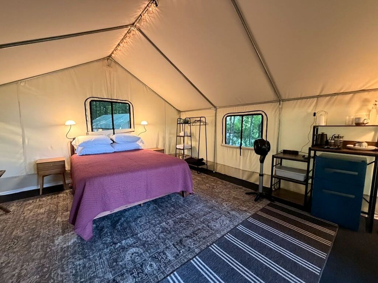 A tent with a bed, a desk, and a window.