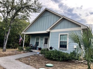 A residential house with a front porch, a mailbox, and a flag. - The Blue Cottage (Granbury)